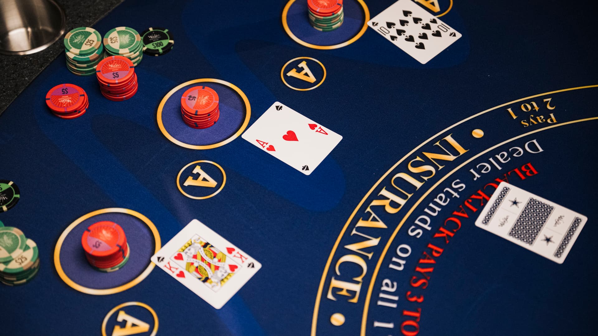Top-down view of a blue blackjack table with playing cards and stacks of betting chips.