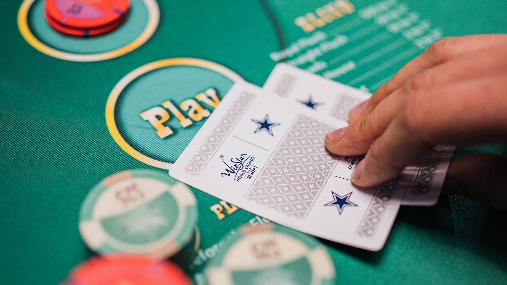 A poker player holding their cards at a Texas Hold'em table.