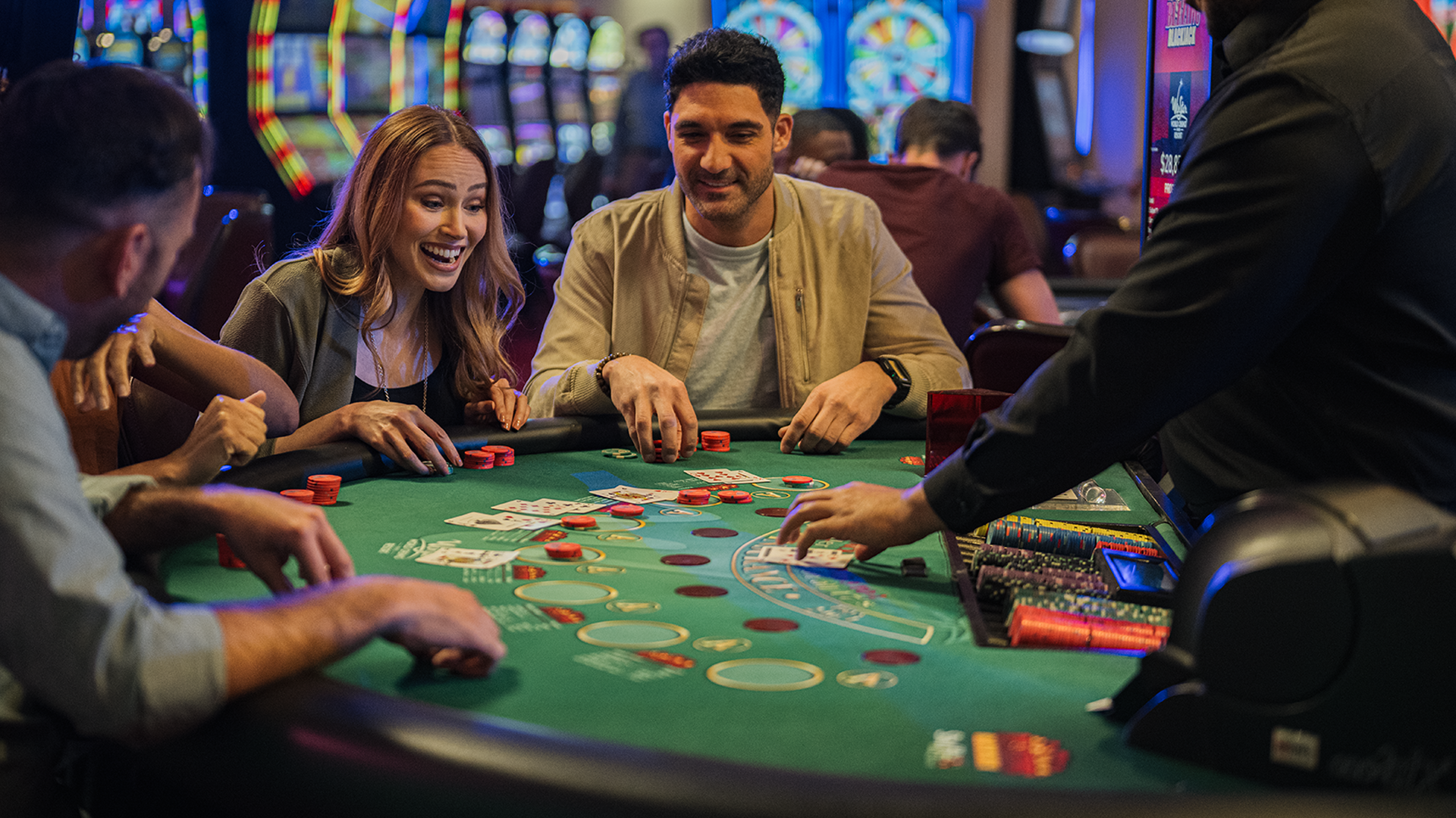Two people smiling and playing blackjack at a casino table.