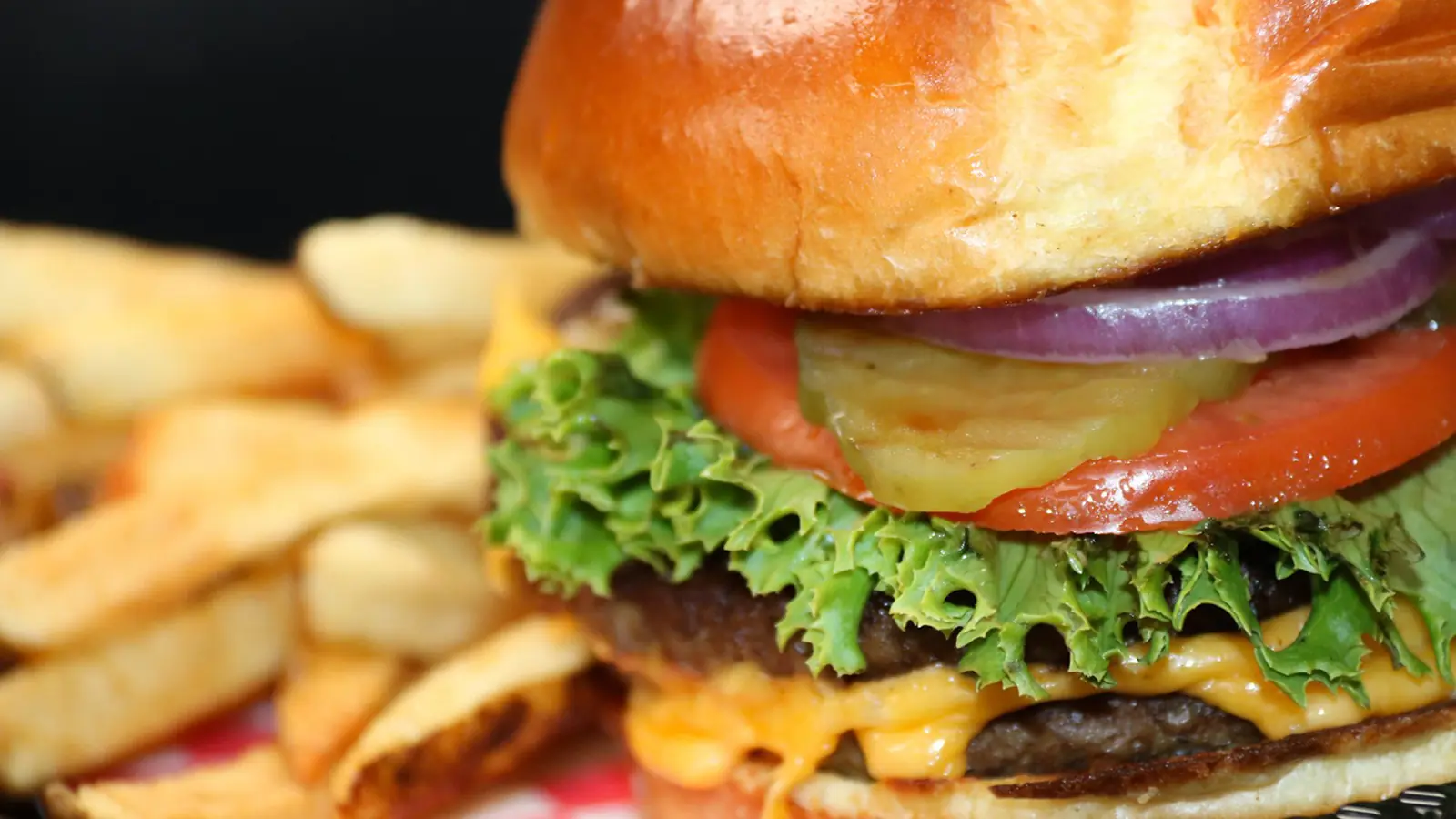 A close up shot of a cheeseburger and fries.