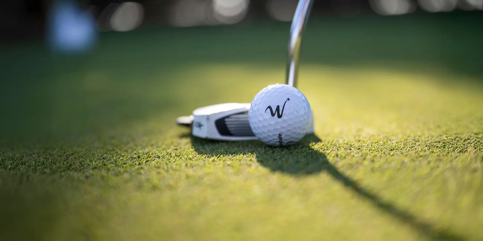 A Putter about to hit a golf ball with a WinStar logo on it.