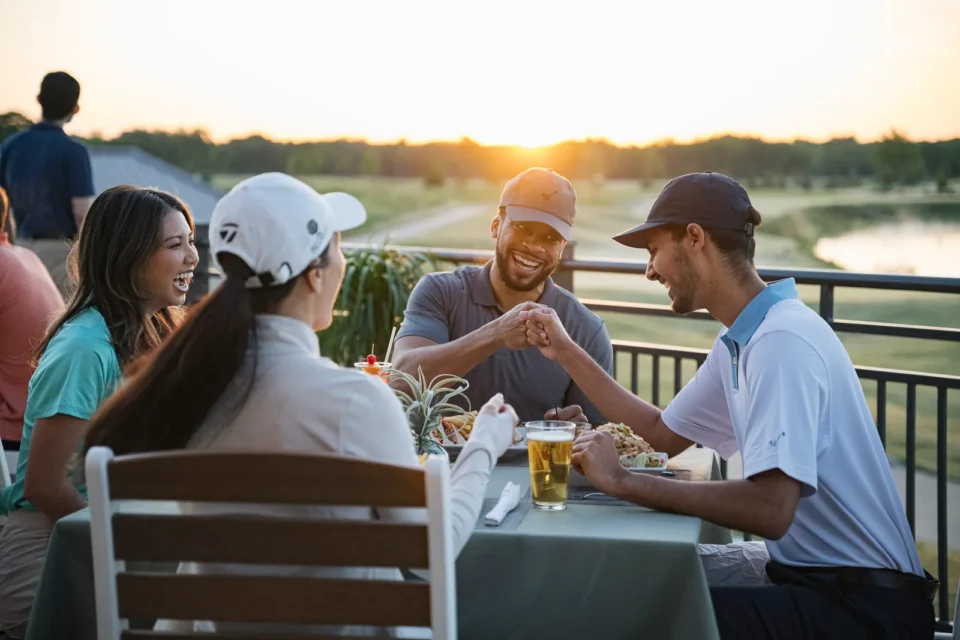 A group enjoying the WinStar Golf Club Clubhouse at sunset.